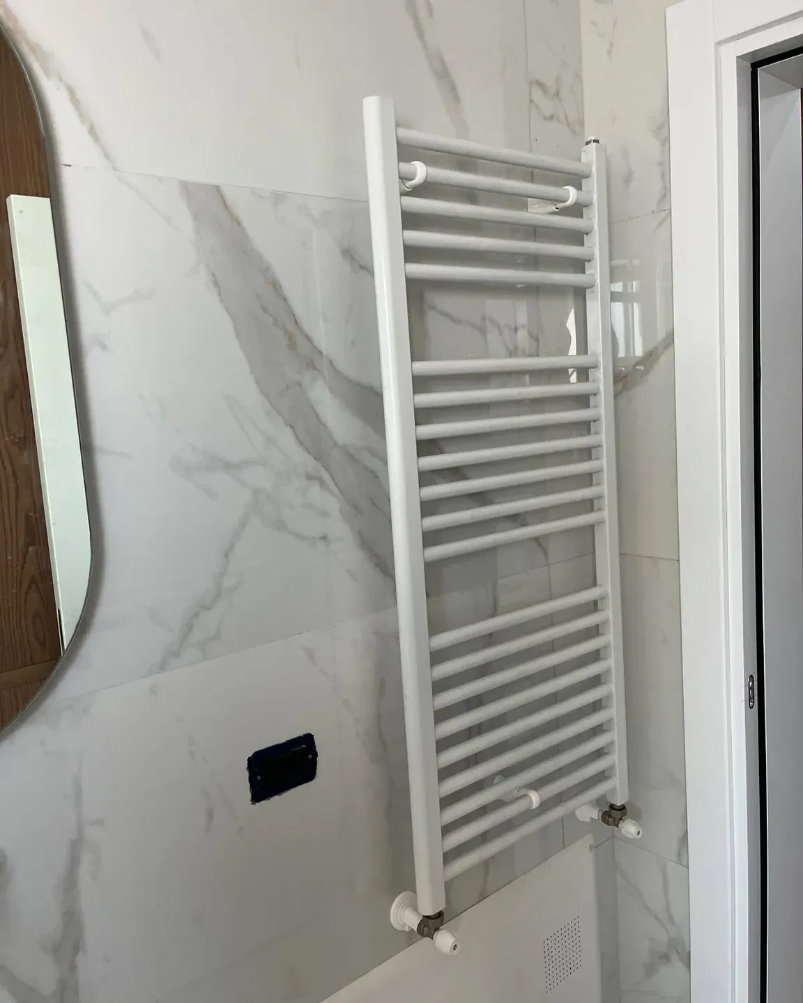 Radiator peshqirash i instaluar në një banjo të veshur me mermer