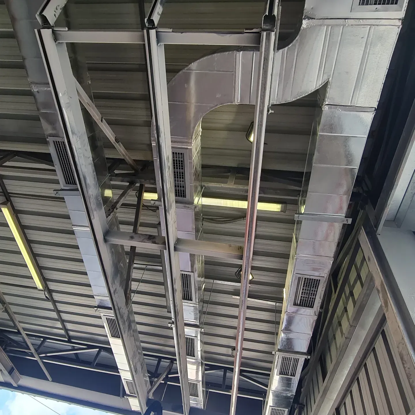 Kanale ventilimi drejtkëndore të montuara në strukturën metalike të një ambienti industrial