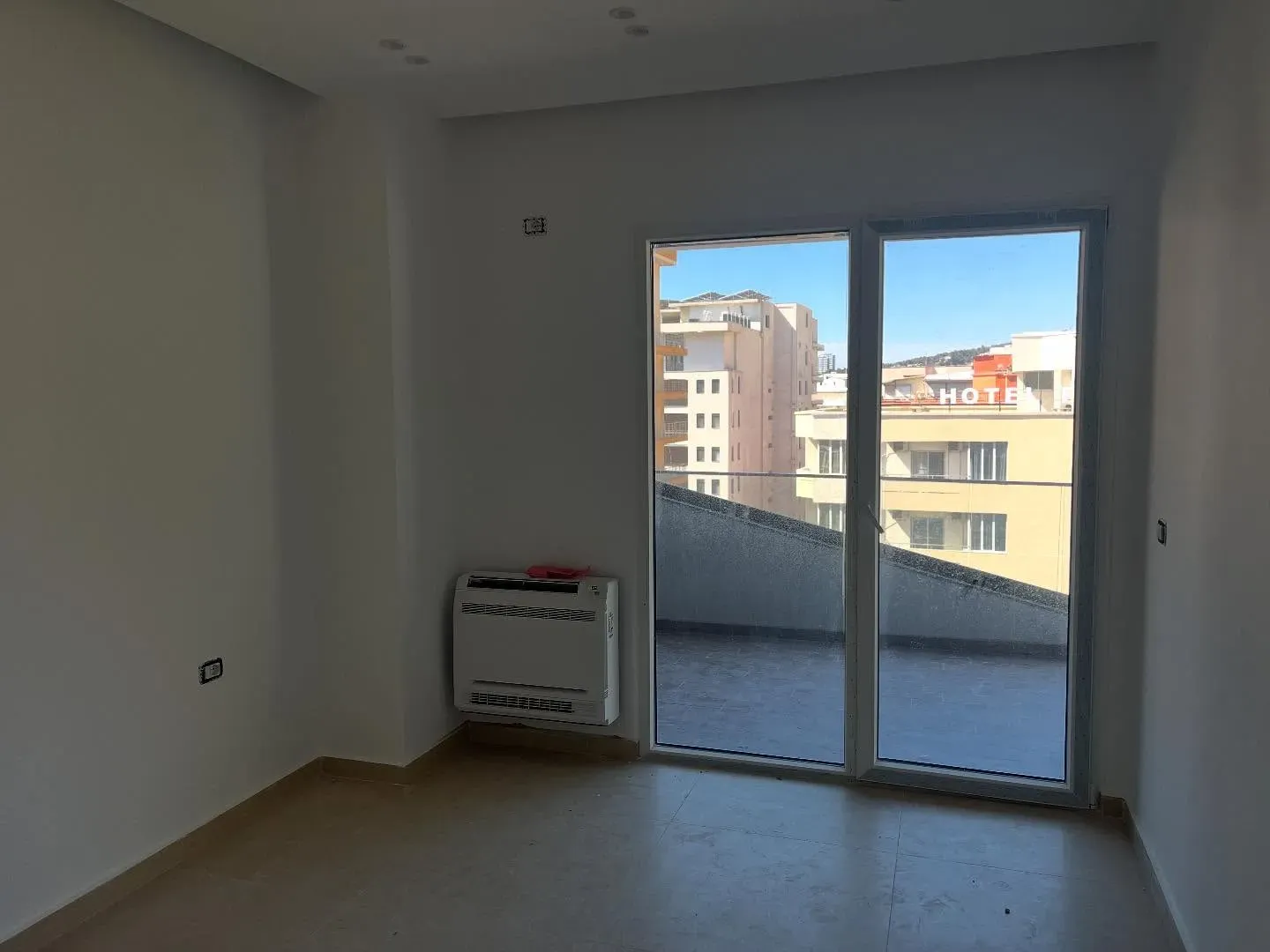Kondicioner dyshemeje i instaluar në një apartament me pamje nga qyteti