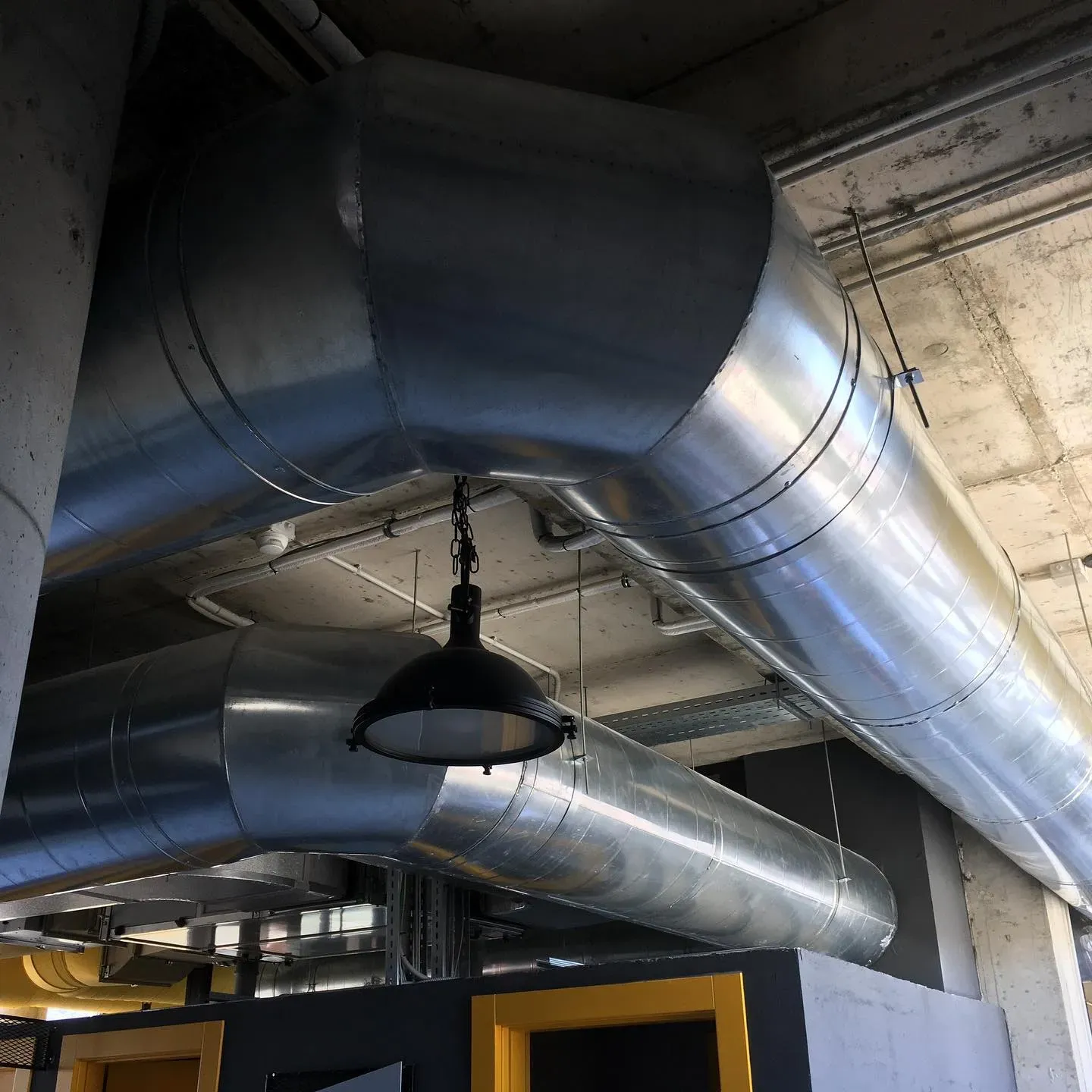 Shpërndarje kanalesh spirale ventilimi në tavanin e një ambienti tregtar