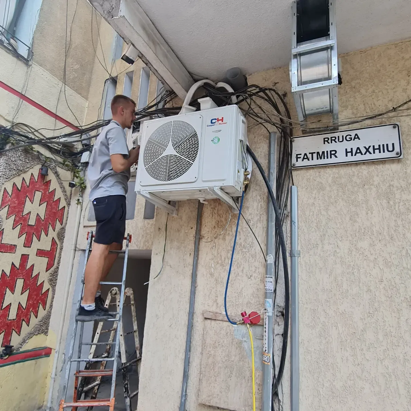 Teknik duke punuar mbi shkallë gjatë instalimit të një kondicioneri